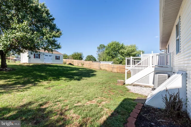 a backyard of a house with plants and large tree