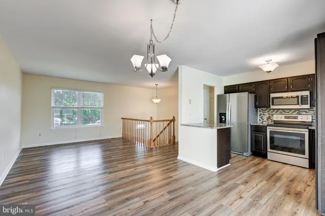 a kitchen with stainless steel appliances granite countertop a refrigerator a stove and a wooden floors