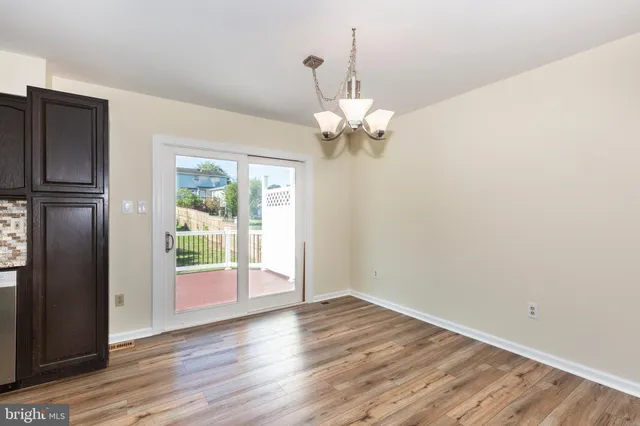 an empty room with wooden floor a ceiling fan and windows