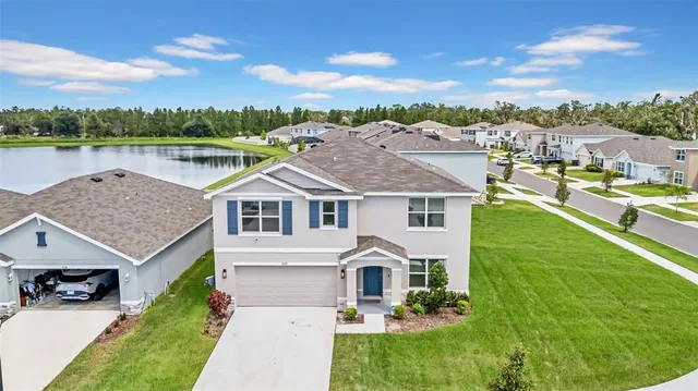 a front view of a house with a garden and lake view