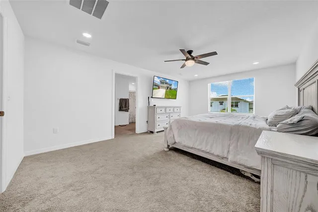 a spacious bedroom with a bed and ceiling fan