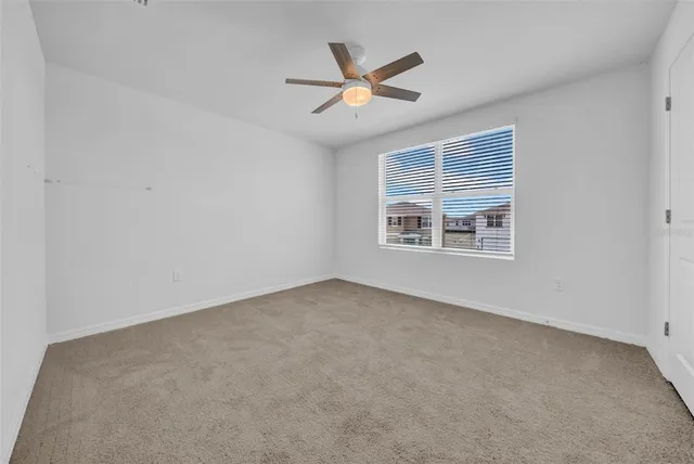 an empty room with ceiling fan and windows