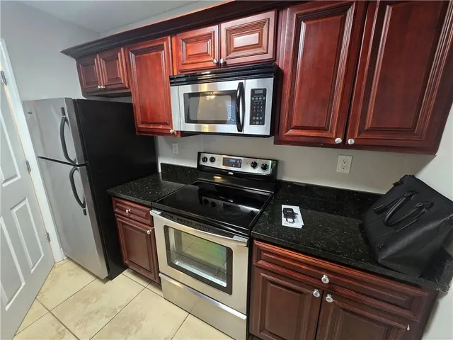 a kitchen with granite countertop a refrigerator stove and microwave