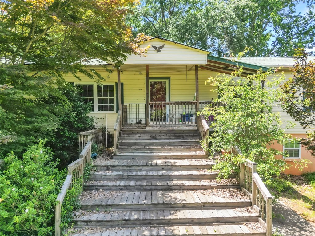 602 Harper Road Pendleton, SC 29670 - Photo 2 of 32 A welcoming front entrance with a long wooden staircase leads to a covered porch.