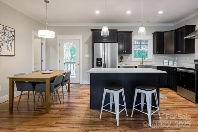 a kitchen with stainless steel appliances kitchen island granite countertop a dining table chairs and sink