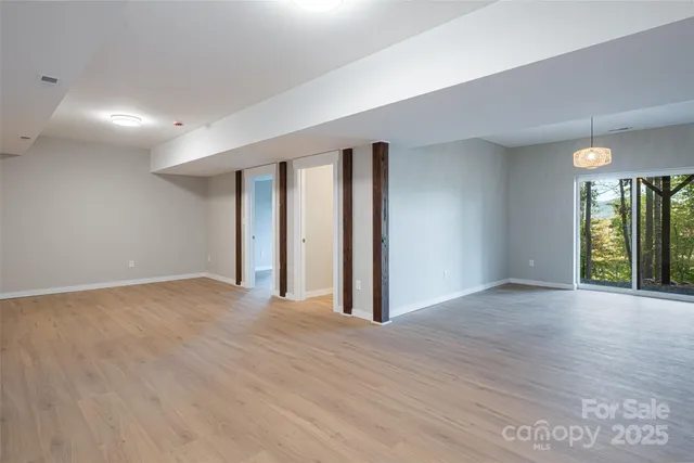 a view of an empty room with window and wooden floor