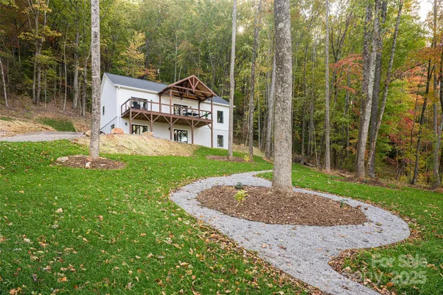 a white house with a small yard and large trees