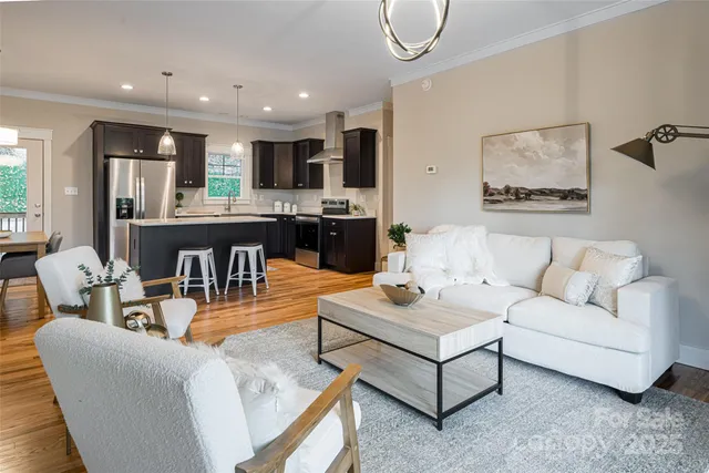 a living room with furniture kitchen view and a large window