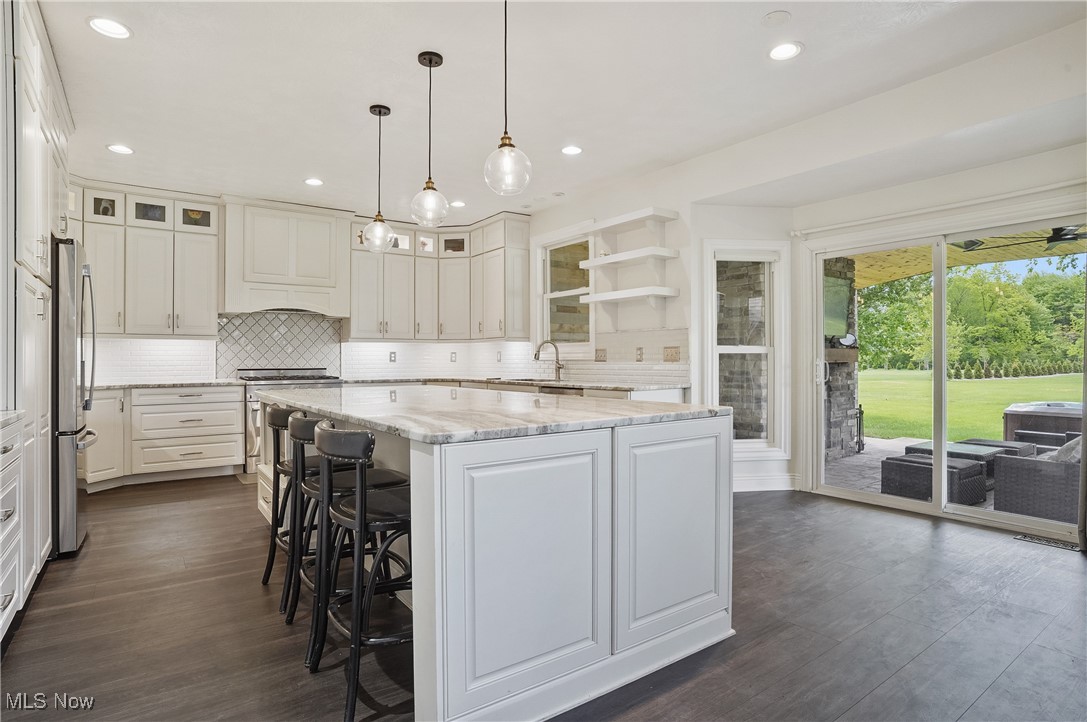 7305 Alexander Road Painesville, OH 44077 - Photo 5 of 50 Kitchen featuring a 9ft granite kitchen island, open shelves, white cabinets, a breakfast bar, and decorative backsplash