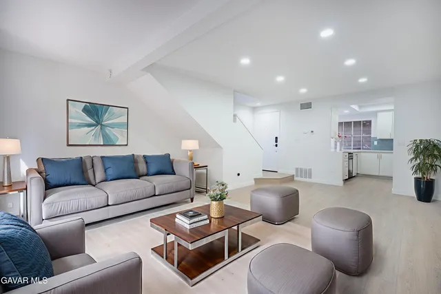 a living room with furniture potted plant and kitchen view