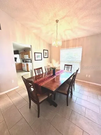 a view of a dining room and livingroom with furniture wooden floor a rug a painting and a chandelier