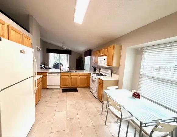 a kitchen with a refrigerator a stove top oven a sink a dining table and chairs