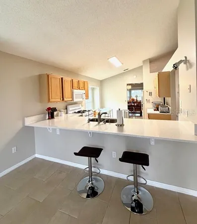 a kitchen with stainless steel appliances kitchen island a stove a sink a refrigerator and chairs