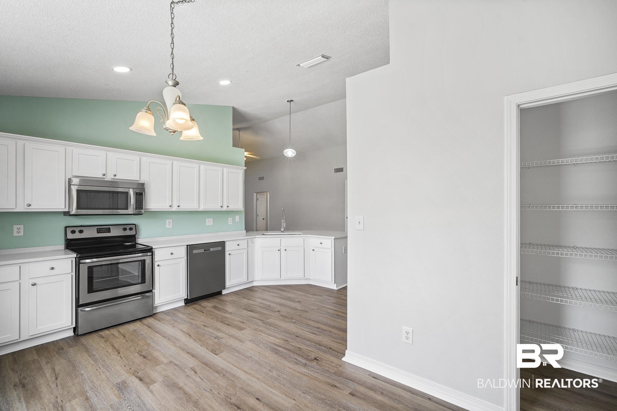 9814 Woolrich Avenue Fairhope, AL 36532 - Photo 7 of 29 Kitchen featuring hanging light fixtures, white cabinets, light wood-type flooring, sink, and appliances with stainless steel finishes
