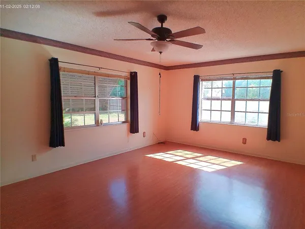 a view of an empty room with window and wooden floor