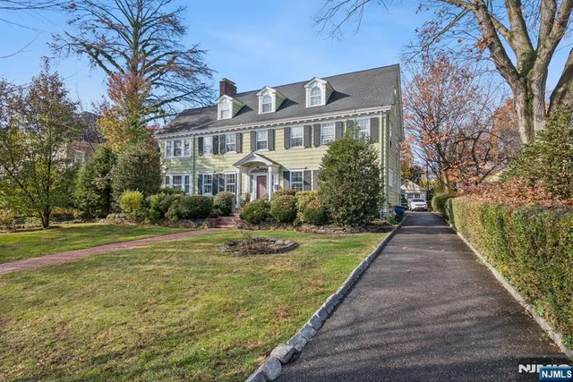 a front view of a house with a garden and trees