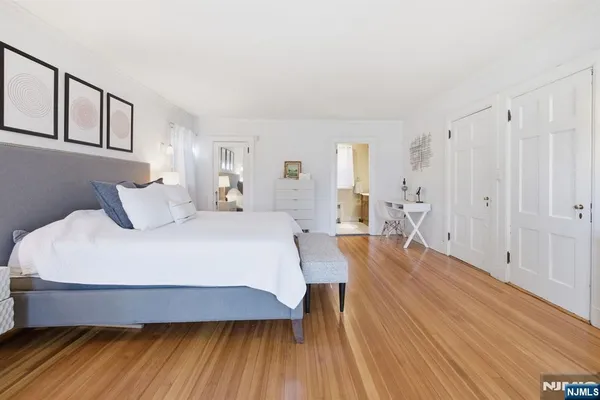 a spacious bedroom with a bed and wooden floor