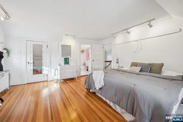 a spacious bedroom with a bed and wooden floor