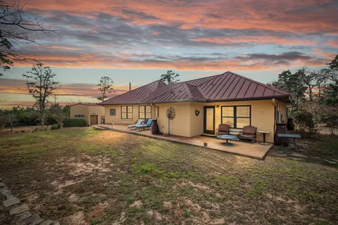 a view of a big house with table and chairs in front of it