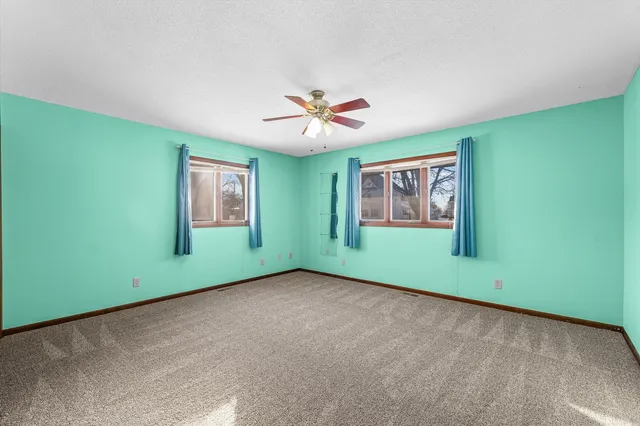 an empty room with window and ceiling fan