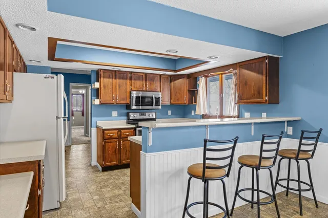 a kitchen with stainless steel appliances kitchen island granite countertop a refrigerator and microwave