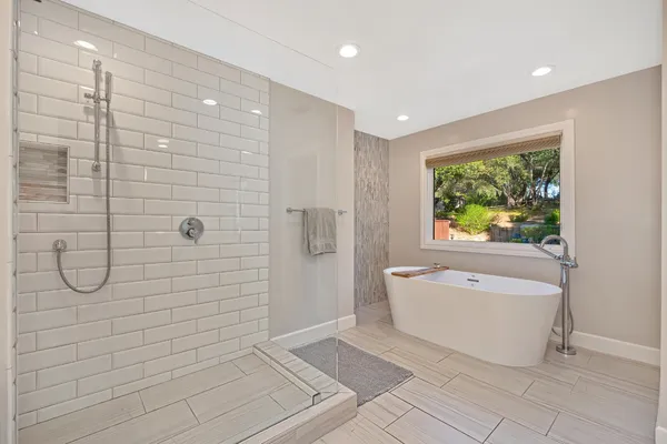 a bathroom with a tub a window and a shower