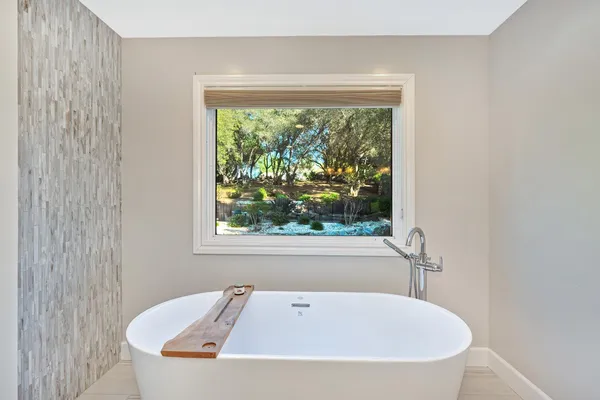 a white bath tub sitting in a bathroom next to a window
