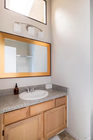 a bathroom with a granite countertop sink and a mirror