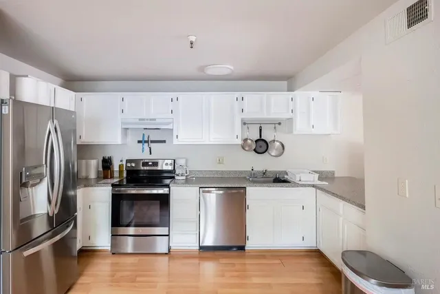 a kitchen with stainless steel appliances granite countertop a stove top oven a refrigerator and a sink