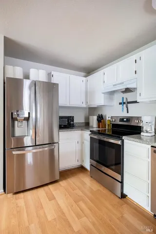 a kitchen with cabinets stainless steel appliances and wooden floor