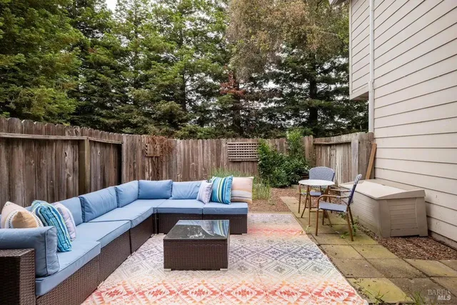 a view of a patio with couches and a table and chairs with wooden fence