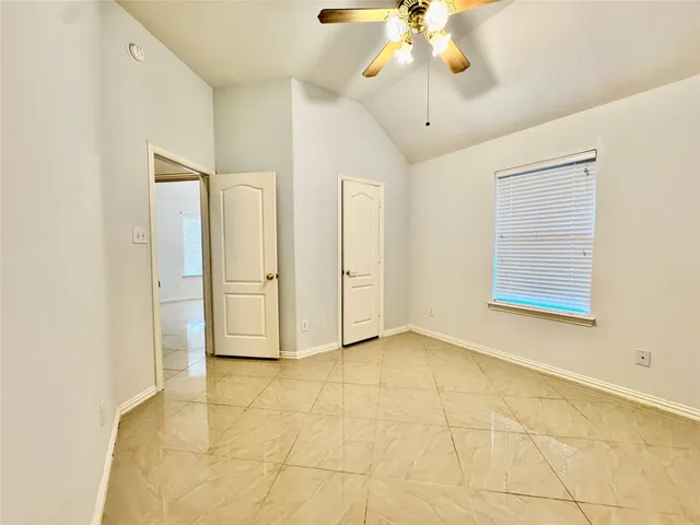 a view of an empty room with chandelier fan and fire place