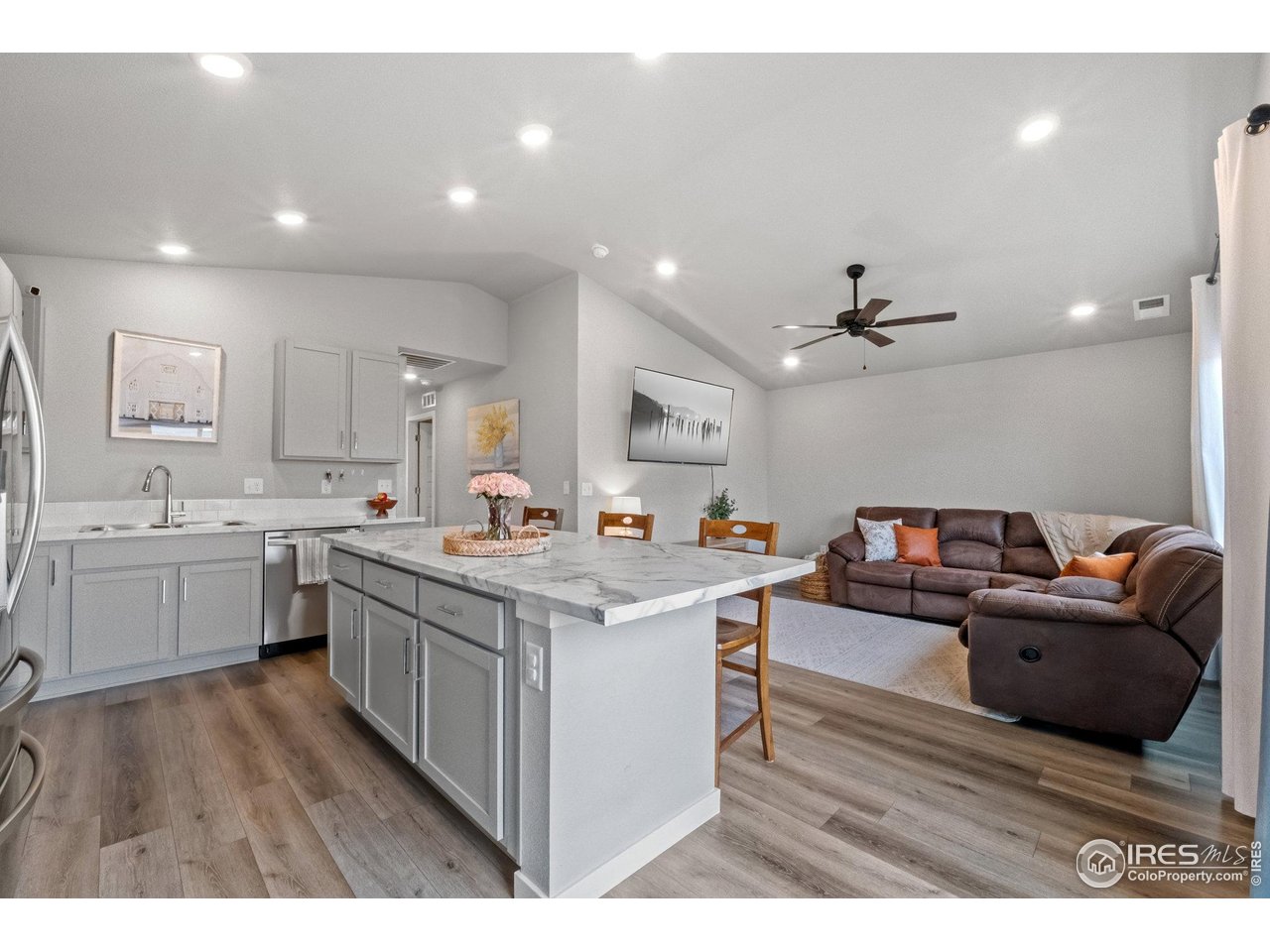 515 Wildcat Parkway Wiggins, CO 80654 - Photo 23 of 43 a open kitchen with stainless steel appliances granite countertop a sink dishwasher stove and white cabinets with wooden floor