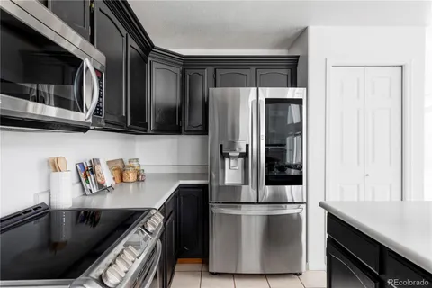 a kitchen with stainless steel appliances granite countertop a refrigerator a stove and a sink with wooden cabinets