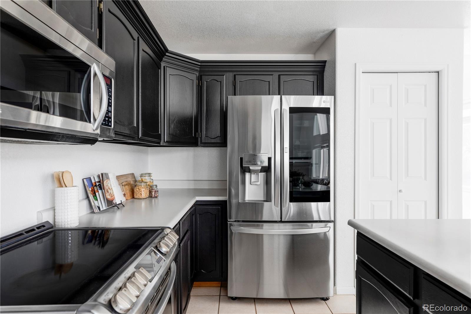 12829 Claude Place Thornton, CO 80241 - Photo 12 of 39 a kitchen with stainless steel appliances granite countertop a refrigerator a stove and a sink with wooden cabinets
