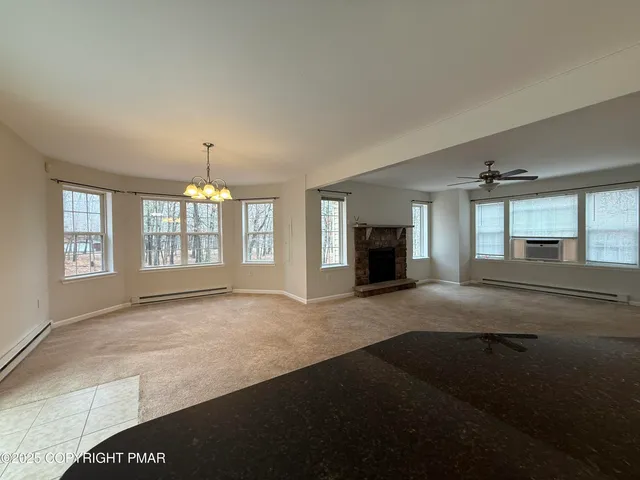 a view of an empty room with a window and fireplace