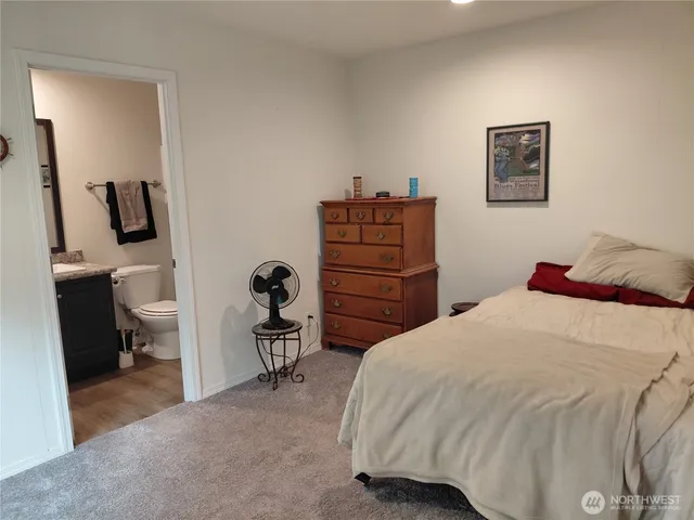 a bedroom with a bed and a flat tv screen on dresser