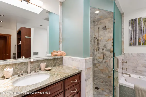 a bathroom with a granite countertop double vanity sink mirror and shower