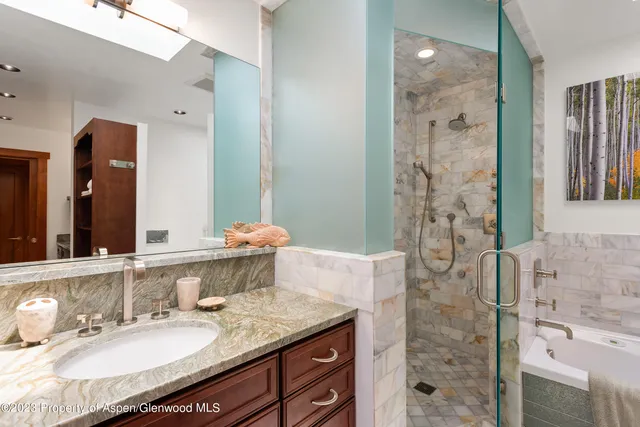 a bathroom with a granite countertop double vanity sink mirror and shower