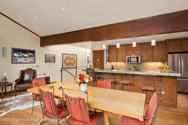 a dining hall with stainless steel appliances granite countertop a dining table and chairs with wooden floor