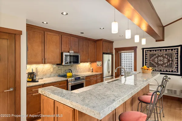 a kitchen with stainless steel appliances granite countertop a stove top oven a sink dishwasher and cabinets with wooden floor