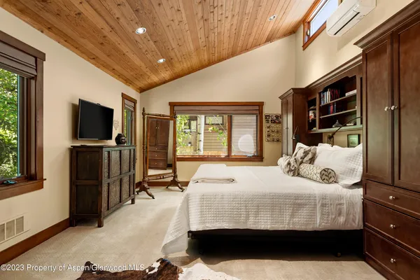 a bedroom with a bed and a flat tv screen on dresser