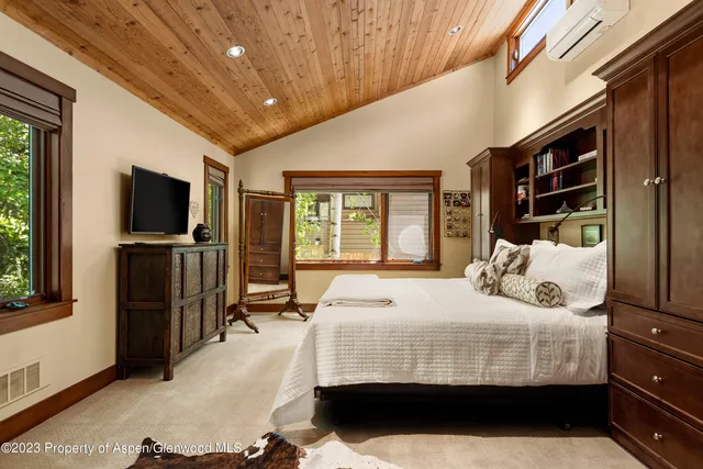 a bedroom with a bed and a flat tv screen on dresser