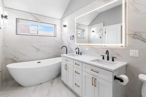 a bathroom with a white tub sink and mirror