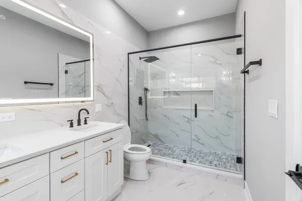 a bathroom with a granite countertop shower sink vanity mirror and toilet