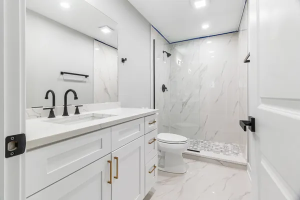 a bathroom with a sink toilet a mirror and shower