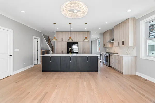 a large kitchen with stainless steel appliances kitchen island a large counter top and a wooden floors