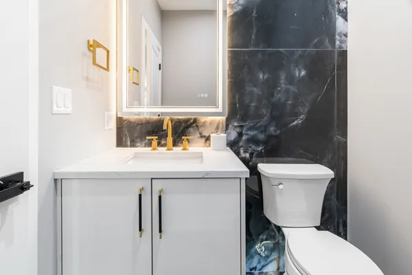 a bathroom with a granite countertop toilet sink and mirror