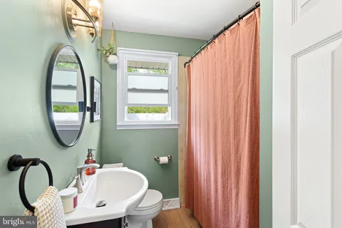 a bathroom with a sink a mirror a toilet and a window