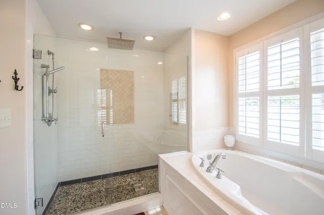 a bathroom with a bathtub a window and a shower
